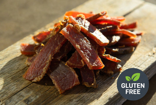 High-quality gluten-free beef jerky strips on a wooden board with gluten-free certification badge – premium snack photography