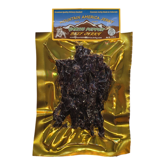 Mountain America Jerky Garlic Pepper Beef Jerky front: gold bag with a window showing dark strips flecked with pepper