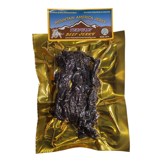 Mountain America Jerky Teriyaki Beef Jerky front: dark strips visible through the clear vacuum-sealed pack on gold foil