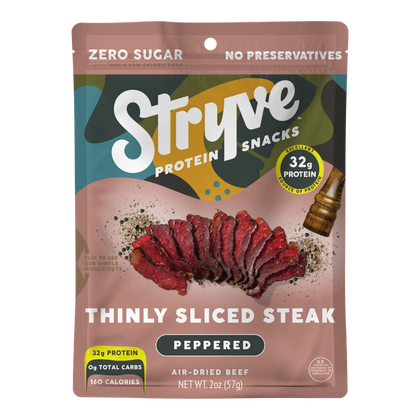 Front of Stryve Peppered air-dried beef bag with thinly sliced steak, cracked pepper, a pepper grinder and zero sugar badge